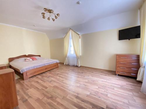 a bedroom with a bed and a dresser and a television at Центрум Делюкс in Lviv