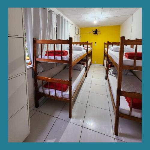 a room with four bunk beds and a yellow wall at Acquarela Hostel in Arraial do Cabo