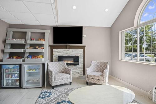 a living room with a fireplace and a flat screen tv at Sonesta Essential Hotel Blue Springs in Blue Springs