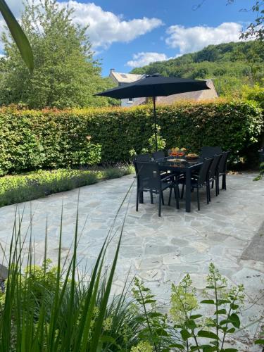a table and chairs with an umbrella on a patio at Maison Hortensia in Tellin