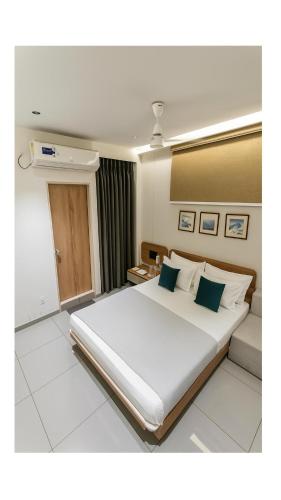 a bedroom with a large white bed with blue pillows at KANT by GoHotels - Near Shree Dwarkadhish Temple in Dwarka
