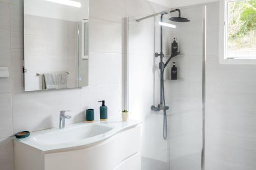 a white bathroom with a sink and a shower at Magnifique villa piscine vue mer à 180 in Sainte-Anne
