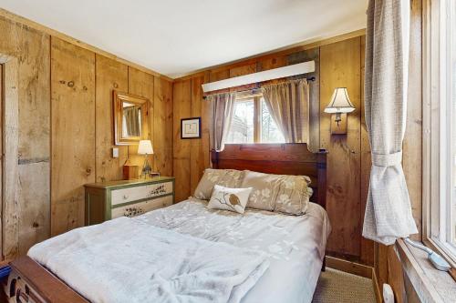 a bedroom with a bed with wooden walls and a window at Mount Abram's Chalet in Greenwood