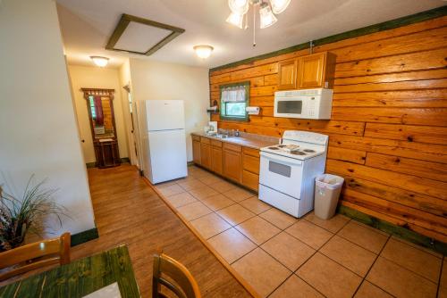 a kitchen with white appliances and wooden walls at Fishtale Lodge Cabins in Buchanan