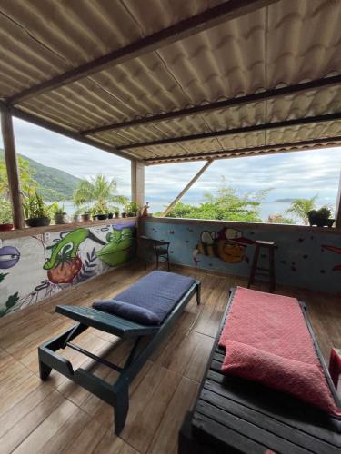 a balcony with a table and a bench and a mural at Pousada Morango das Palmas in Praia de Palmas