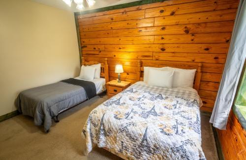 two beds in a room with a wooden wall at Fishtale Lodge Cabins in Buchanan