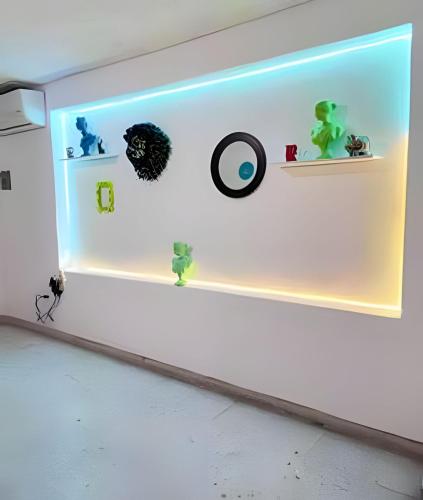 a light on a white wall with shelves and clocks at Amplia planta baja Fundidora in Monterrey