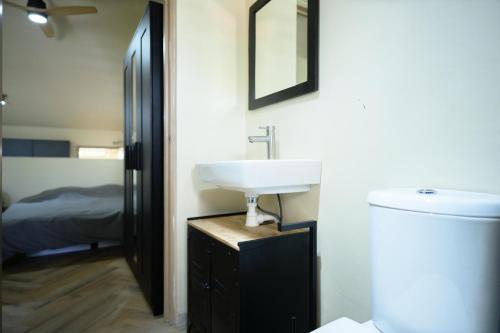 ein Badezimmer mit Waschbecken und Toilette und ein Bett in der Unterkunft Aki Banda Suites in Willemstad