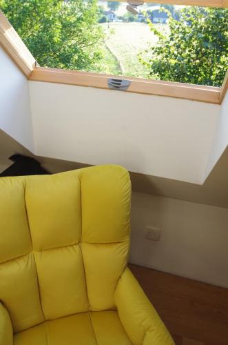 a yellow couch in a room with a window at Hiška na skalci, The House on the Rock in Krka