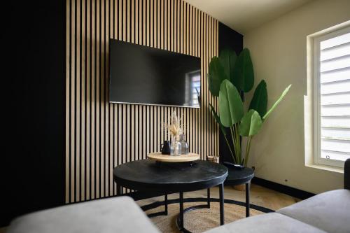 ein Wohnzimmer mit einem Tisch und einem TV an der Wand in der Unterkunft Aki Banda Suites in Willemstad