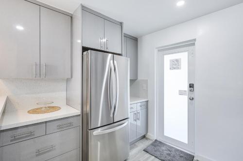 a kitchen with white cabinets and a stainless steel refrigerator at 8 Mi to Design District Miami Home with Yard in Miami
