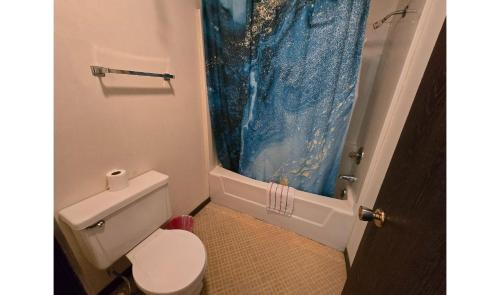 a bathroom with a toilet and a blue shower curtain at OYO Sandman Inn in Eagle Grove