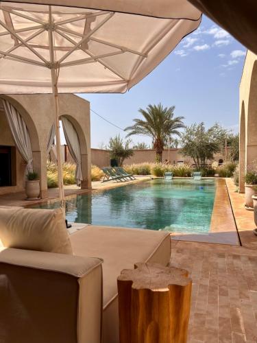 a swimming pool with an umbrella and a couch and a chair at Villa Cactus & chill - Breakfast included! in Marrakech