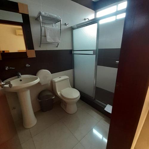 a bathroom with a toilet and a sink and a shower at Corona Real Hotel in Guayaquil