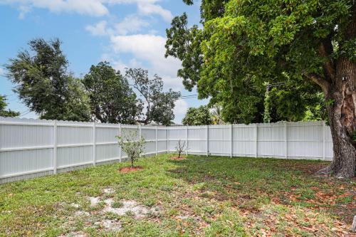 a white fence with a tree in a yard at 8 Mi to Design District Miami Home with Yard in Miami