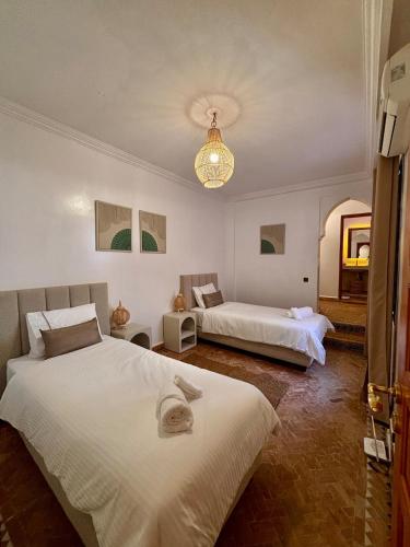 a bedroom with two beds and a chandelier at Villa Cactus & chill - Breakfast included! in Marrakech