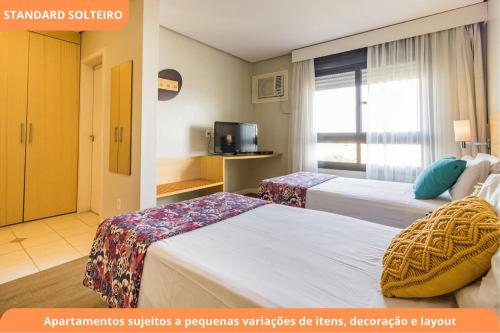 a hotel room with two beds and a television at Century Park by My Way in Porto Alegre