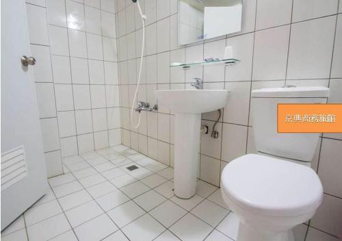 a white bathroom with a toilet and a sink at Jing Dian Business Hotel in Taoyuan