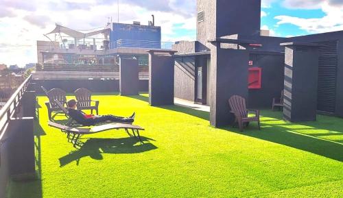 a woman is sitting on a balcony on a roof at Parque 93 apartamento ideal in Bogotá