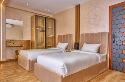 a bedroom with two beds and a mirror at Cleo Patra Pyramids Tower Inn in Banī Ghālib