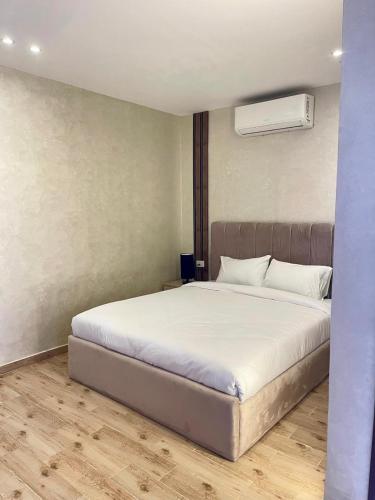 a bedroom with a white bed and a air conditioner at Cleo Patra Pyramids Tower Inn in Banī Ghālib
