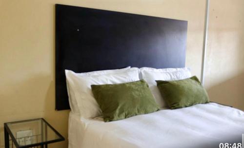 a bed with white sheets and green pillows at 54 River Logde in Mokopane