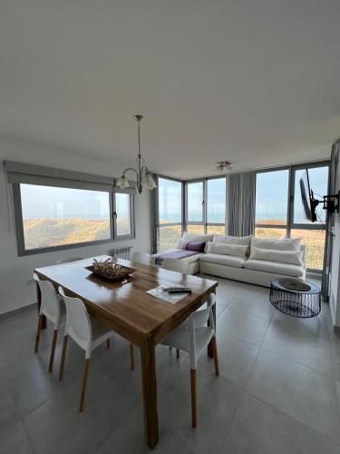 a living room with a table and a couch at Departamento de lujo frente al mar con vista panorámica, pileta y cochera privada in Monte Hermoso