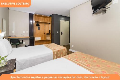 a hotel room with two beds and a tv at Century Park by My Way in Porto Alegre