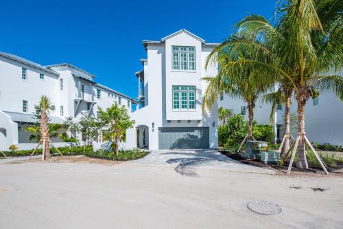 a white house with palm trees in front of it at Sea Glass Cove by SoFLA Vacations in Marathon
