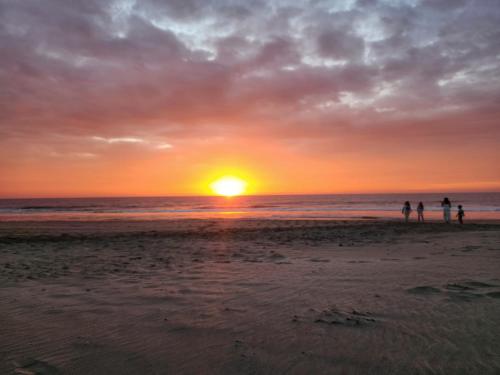 people standing on the beach watching the sunset at Casa Dunas Vichayito in Vichayito