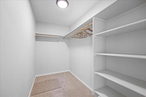a walk in closet with white walls and white shelves at Heart of Caldwell- HotTub-Fenced Yard- Spacious in Caldwell