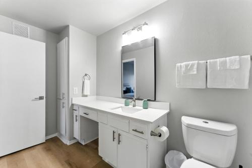 a white bathroom with a toilet and a sink at The Calvin Spacious 334 I 2 Bed 1 Bath in Plano