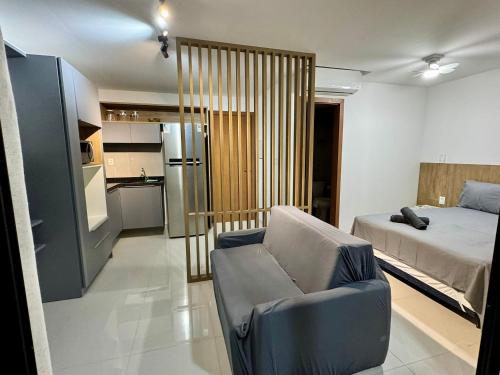 a bedroom with a bed and a couch and a kitchen at UNU 602 Itapuã: piscina, academia, praia e+ in Salvador