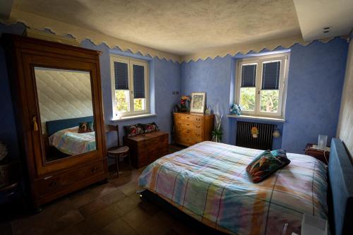 a bedroom with blue walls and a bed and windows at Casa Maddalena in Vicoforte