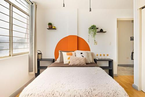 a bedroom with a large bed with an orange headboard at Moderno departamento centro Histórico Monterrey in Monterrey