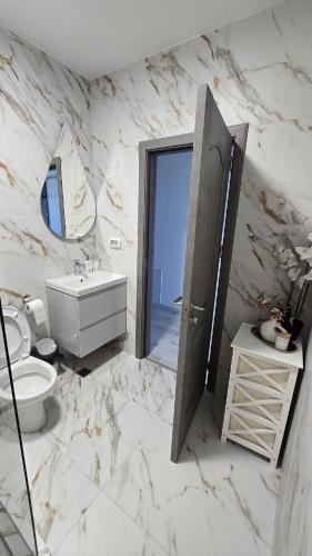 a white marble bathroom with a toilet and a sink at Coquette Appart in Eforie