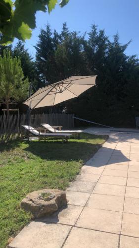 - une table de pique-nique avec un grand parasol dans l'herbe dans l'établissement Maison de charme provençale en pierre, à Puyvert