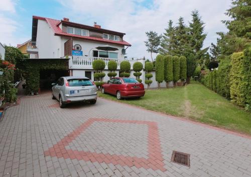 a house with two cars parked in a driveway at Dom Gościnny Wika in Rewal