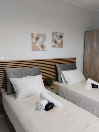 two beds in a room with white sheets at Theo Luxury Apartment in Nea Peramos