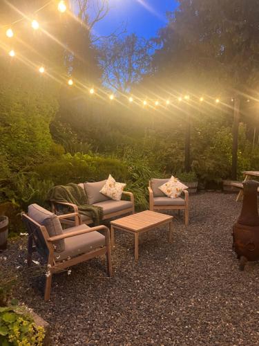 un patio con 2 sedie, un tavolo e luci di Sparrows Nest Holiday Cottage ad Amroth