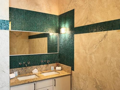 a bathroom with two sinks and green tiled walls at Condado Laguna Villa w Pool 5 Bd 3 Ba - Generator in San Juan