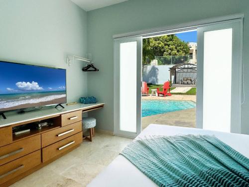 a bedroom with a bed and a tv and a pool at Condado Laguna Villa w Pool 5 Bd 3 Ba - Generator in San Juan