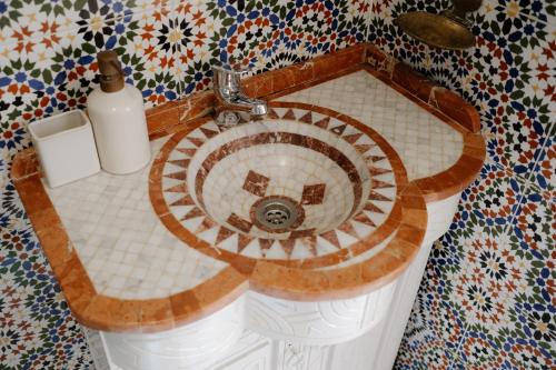 a bathroom with a sink in a mosaic wall at Riad Searenity in Tamraght Ouzdar
