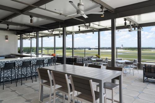 a dining room with tables and chairs and windows at Hyatt Place Melbourne Airport, Fl in Melbourne