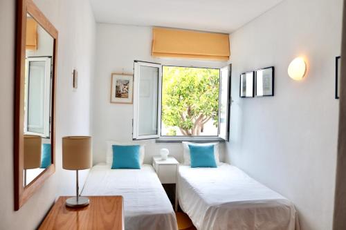 two beds in a room with a window at Casa Mareta in Sagres