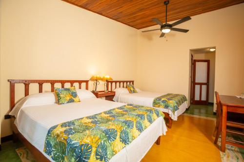 a bedroom with two beds and a desk at Lake Arenal Hotel & Brewery in Tilarán