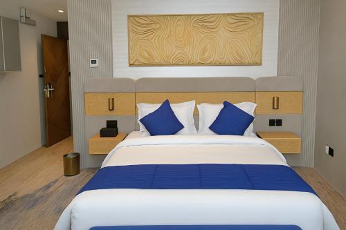a bedroom with a large bed with blue pillows at Elite Served Apartments - Al Cornich in Jeddah