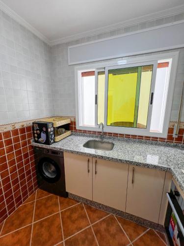 a kitchen with a sink and a window and a washing machine at Appart-Hôtel Costa Azul - Bilal in Tetouan