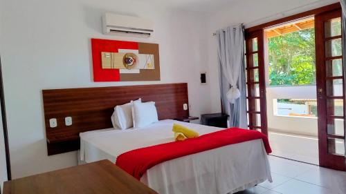 a bedroom with a large bed with a red blanket at Pousada castelo princesinha do Sul in Ilhéus