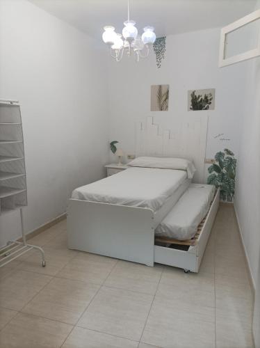 a white bedroom with a bed and a chandelier at Apartamento O Vento in O Grove